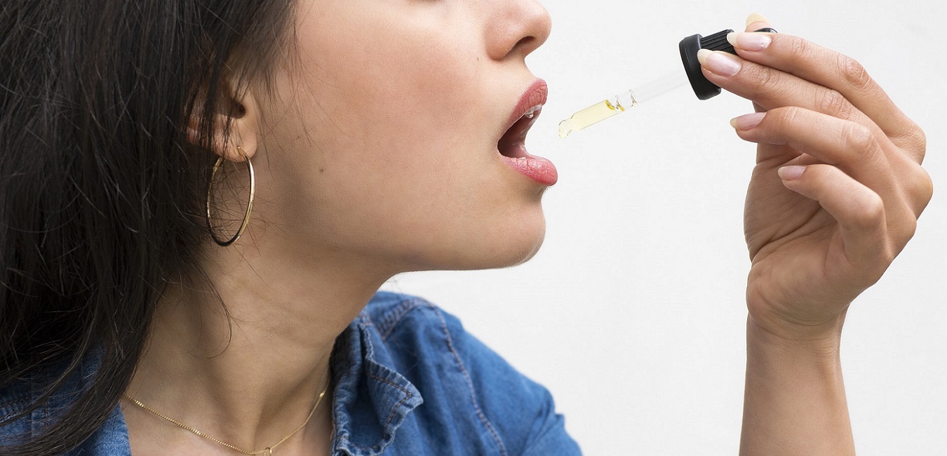 Eine Frau nimmt CBD-Öl mit einer Pipette in den Mund