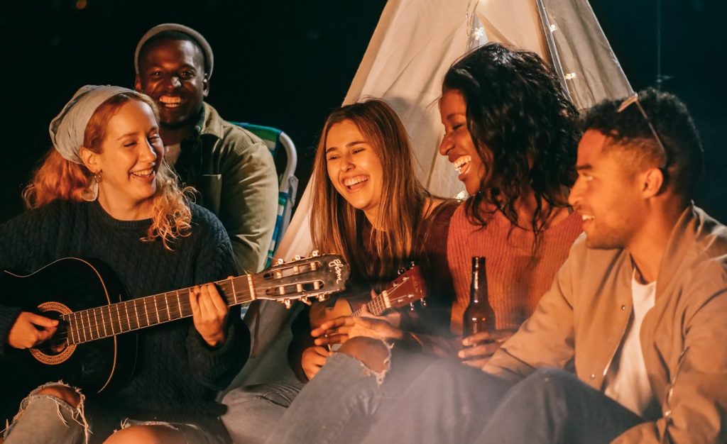 Eine Gruppe von Menschen entspannt sich am Strand unter dem Sternenhimmel.