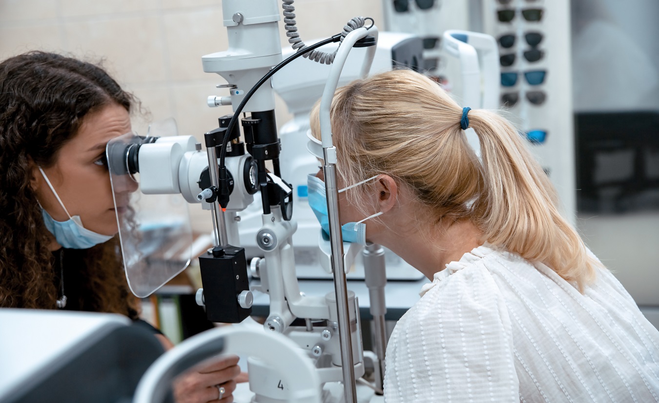 Frau sitzt ruhig bei der Augenärztin, während die Ärztin mögliche Anzeichen von Multipler Sklerose und ein Gerstenkorn untersucht.