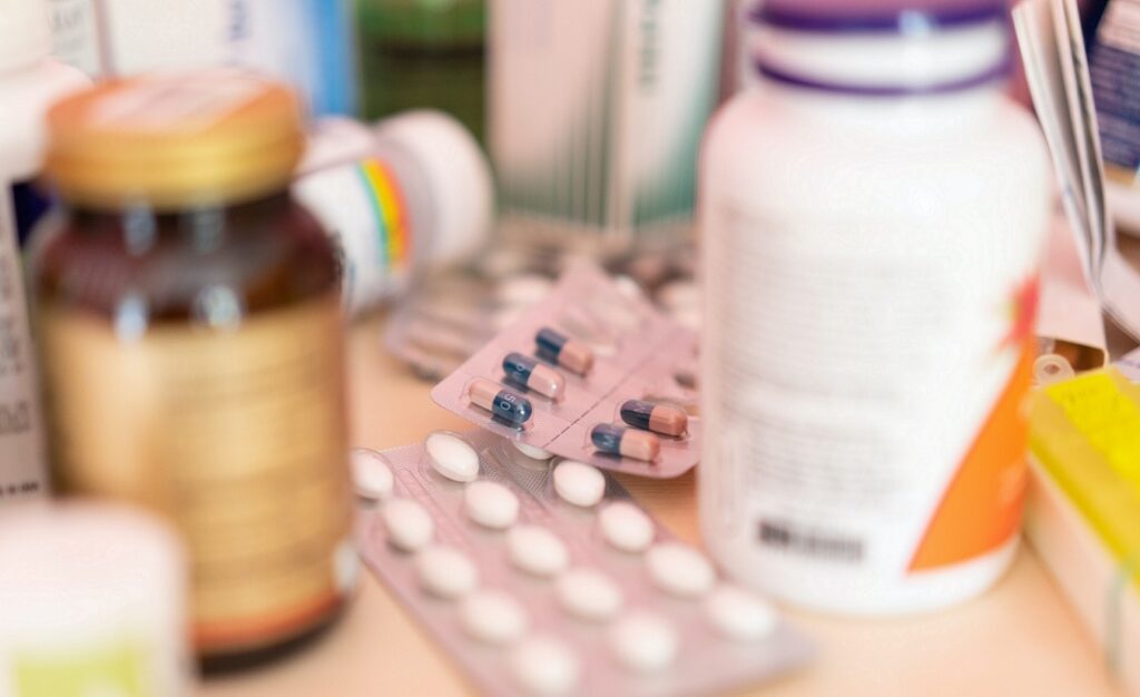 Bunte Palette von Nahrungsergänzungsmitteln, darunter Dosen, Blisterpackungen und Pillen in verschiedenen Formen und Farben auf einem Tisch.