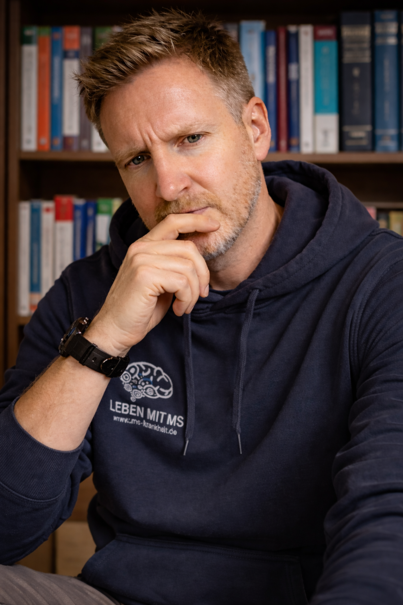 Grübelnder Mann vor medizinischen Fachbüchern zum Thema MS