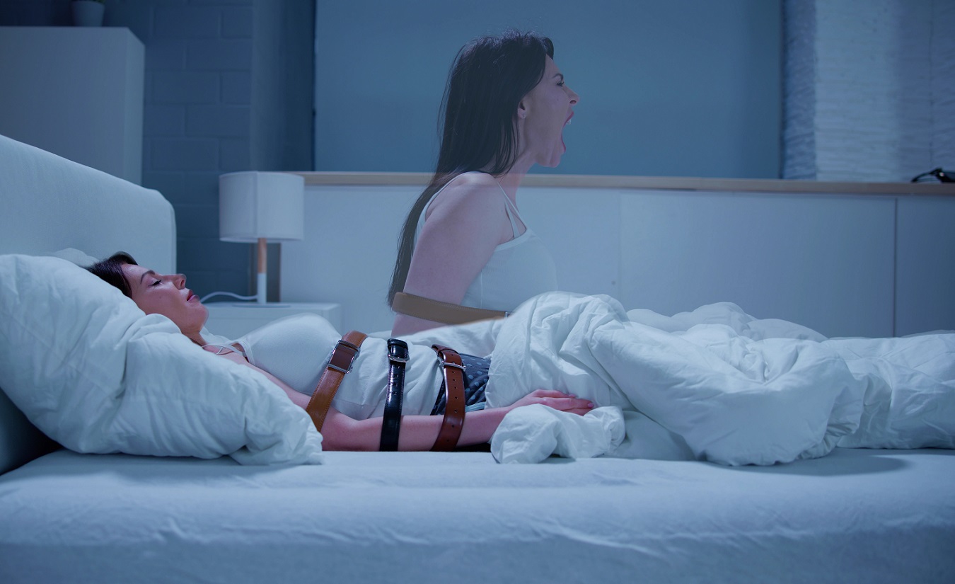 Eine Frau liegt im Bett, ihre Arme sind mit Gürteln am Körper befestigt. In der nächsten Szene sitzt sie befreit im Bett und schreit ihre Verzweiflung heraus.