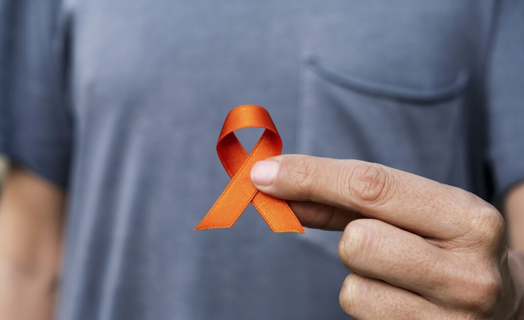 Ein Mann hält eine orangefarbene Schleife als Symbol der Unterstützung für Menschen mit MS.
