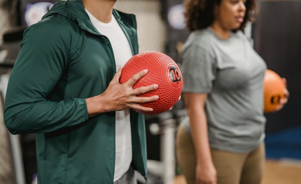 Ein Mann und eine Frau beim Rehasport, halten jeweils einen Ball in den Händen.