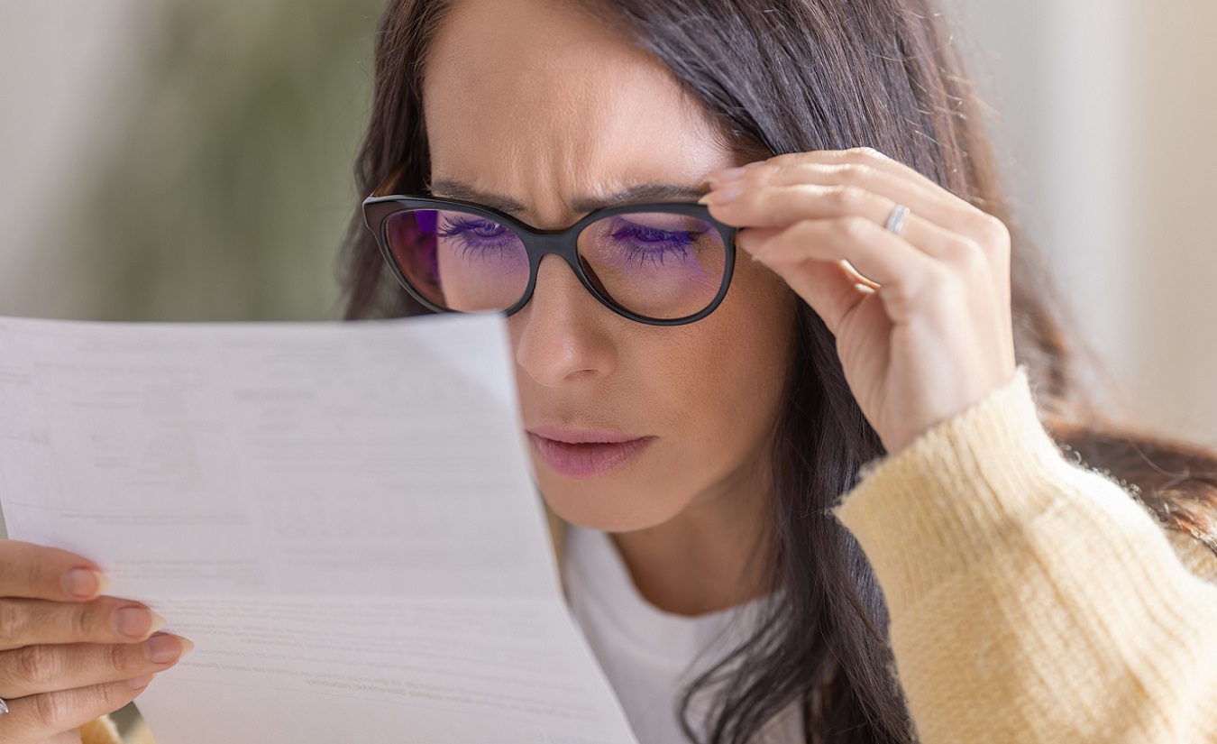 Frau mit Brille liest einen Befund aus nächster Nähe, symbolisiert das Verständnis von Abkürzungen rund um die MS