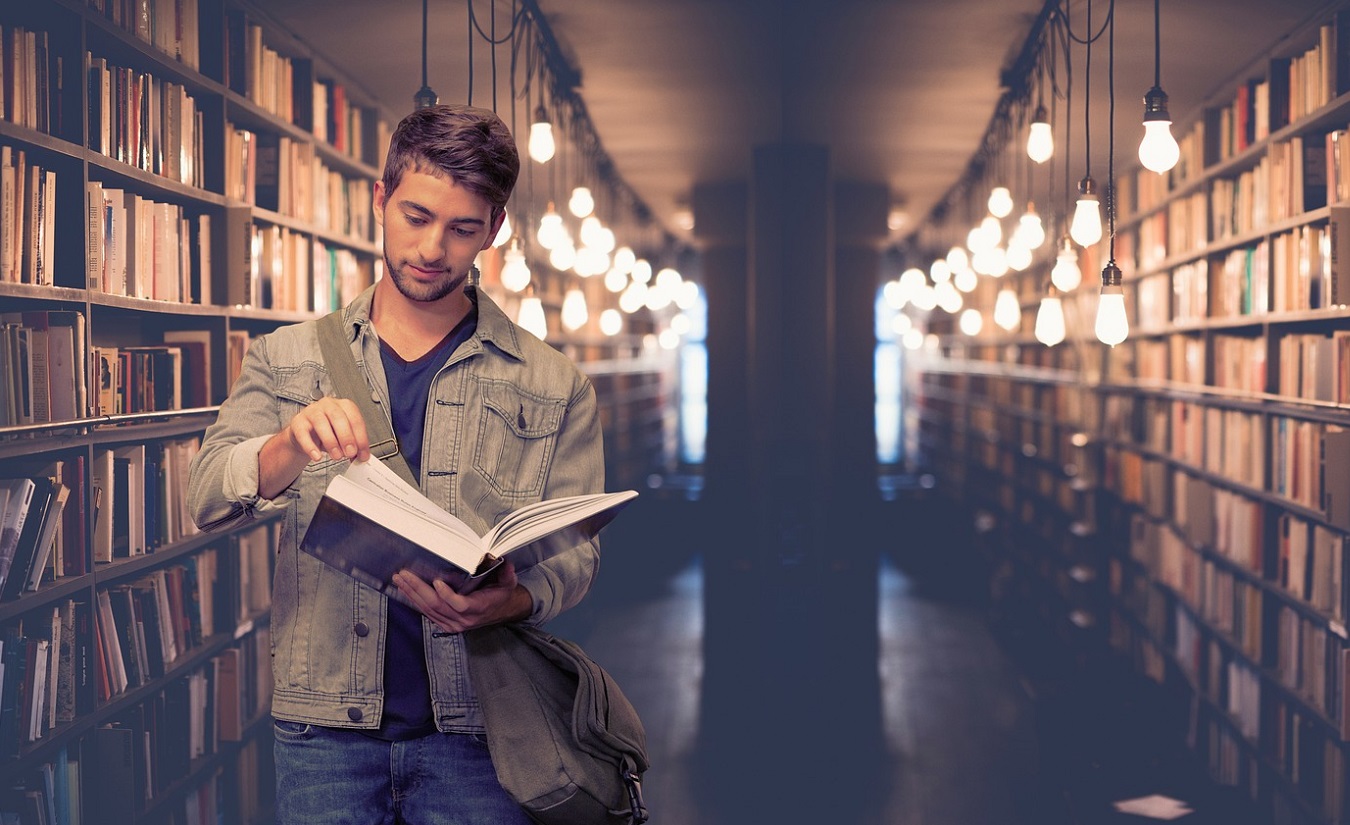 Student blättert in einem Buch in der Bücherei