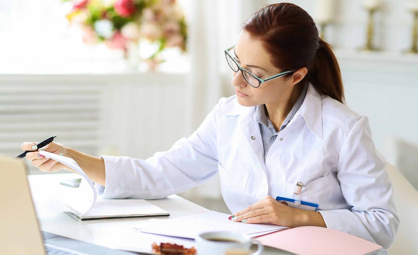 Eine MS-Nurse sitzt am Schreibtisch und erledigt Papierkram. Symbolbild für die Unterstützung und Beratung von MS-Schwestern für Menschen mit Multipler Sklerose.